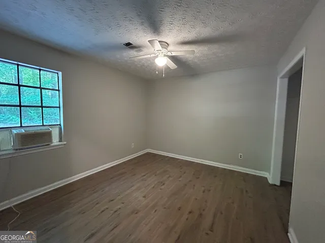 an empty room with wooden floor fan and windows