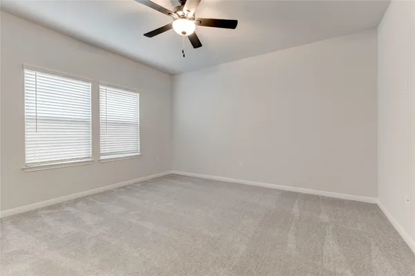 an empty room with windows and fan