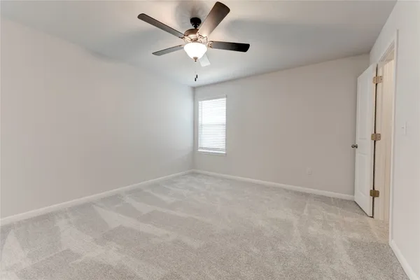 an empty room with a window and a fan