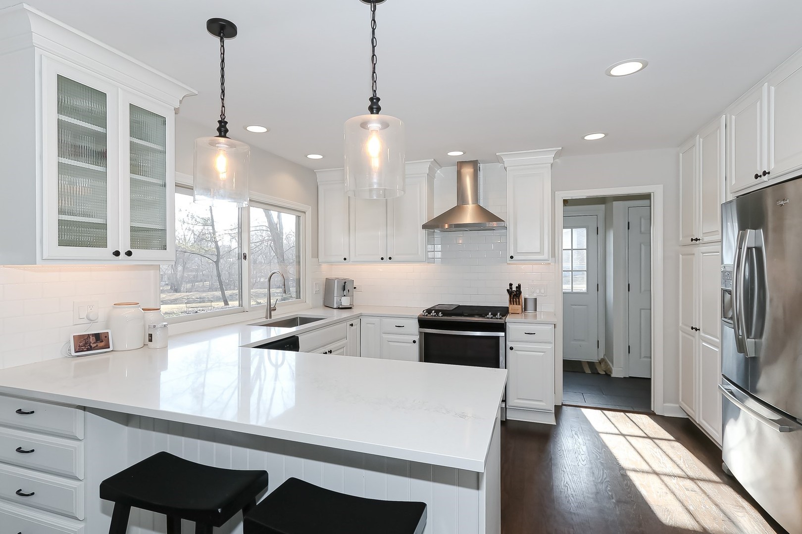 879 Georgetowne Lane Barrington, IL 60010 - Photo 5 of 44 a kitchen with stainless steel appliances a refrigerator a sink a stove a kitchen island and couches with wooden floor