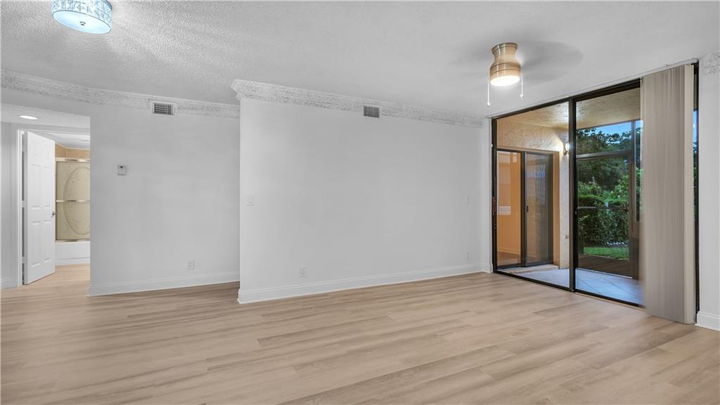 5681 Riverside Drive, Unit 101A6 Coral Springs, FL 33067 - Photo 5 of 24 a view of an empty room with wooden floor and a window