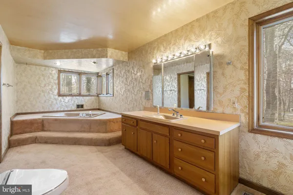 a spacious bathroom with a tub sink and mirror