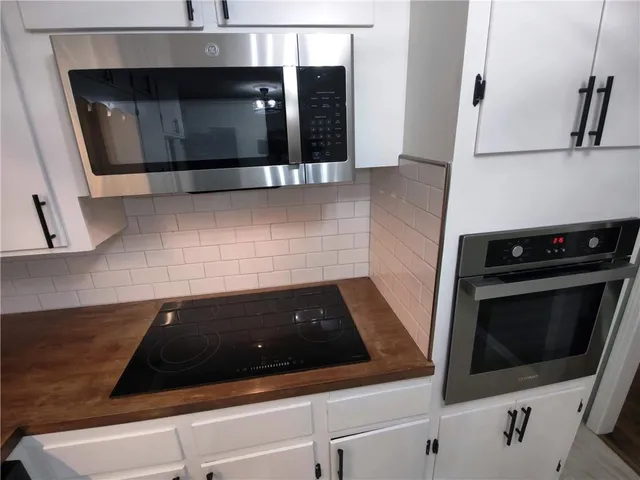 a kitchen with granite countertop white cabinets and stainless steel appliances