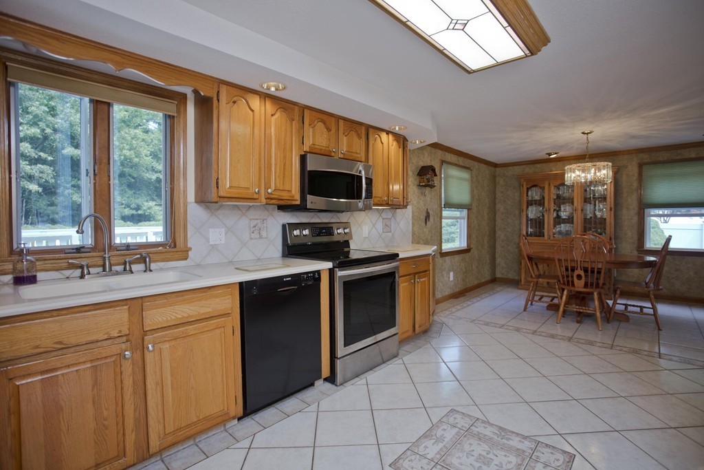 97 Calley Street Springfield, MA 01129 - Photo 11 of 30 a kitchen with stainless steel appliances granite countertop a stove top oven a sink dishwasher a dining table and chairs with wooden floor
