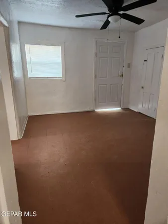 an empty room with a window and a fan