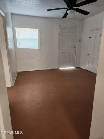 an empty room with a window and a fan