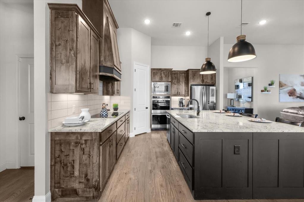 329 Palo Alto Drive Springtown, TX 76082 - Photo 12 of 34 Kitchen featuring an expansive island with a built-in sink, pendant lighting, white subway tile backsplash, and stainless steel appliances