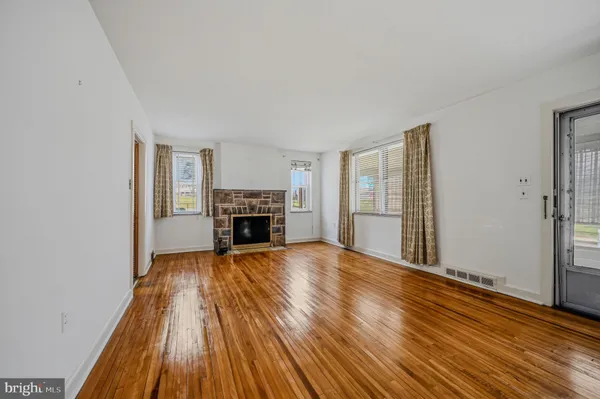 an empty room with wooden floor fireplace and windows