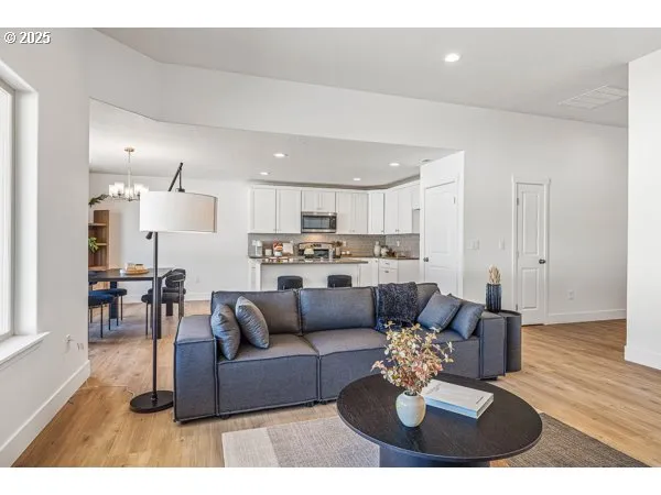 a kitchen with stainless steel appliances granite countertop a stove top oven a sink a dining table and chairs with wooden floor