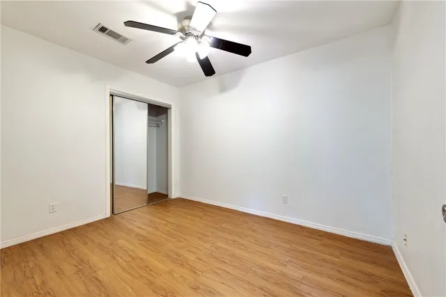 an empty room with wooden floor and ceiling fan