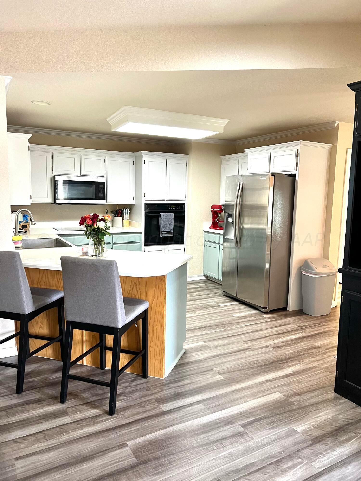 5801 South Bowie Street Amarillo, TX 79118 - Photo 8 of 23 a kitchen with stainless steel appliances kitchen island granite countertop a refrigerator a stove top oven a sink dishwasher and white cabinets with wooden floor