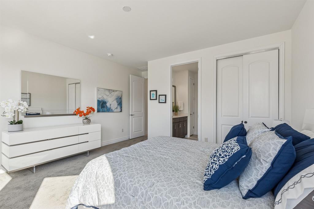 8717 Basanite Avenue Denton, TX 76207 - Photo 23 of 30 a bedroom with a white bed and a large mirror