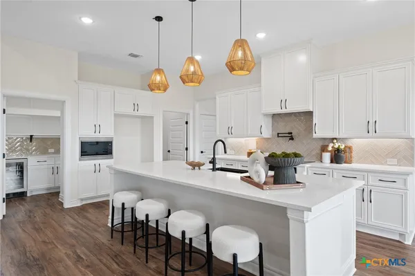 a kitchen with stainless steel appliances granite countertop a stove a sink dishwasher and white cabinets with wooden floor