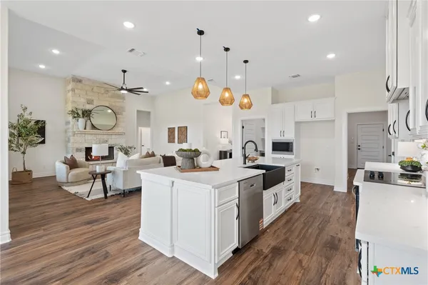 a large kitchen with cabinets a sink a stove and wooden floor