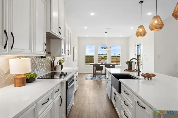 a kitchen with kitchen island stainless steel appliances a sink a stove and a wooden floors