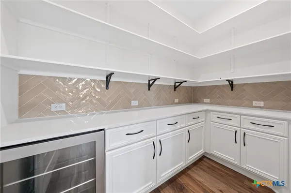 a kitchen with granite countertop white cabinets and wooden floor