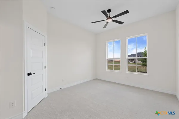 a view of an empty room with a window and a ceiling fan