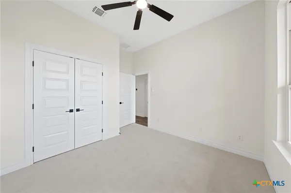 an empty room with a window and a ceiling fan