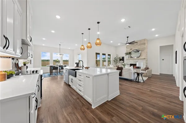 a large white kitchen with lots of counter space wooden floor and appliances
