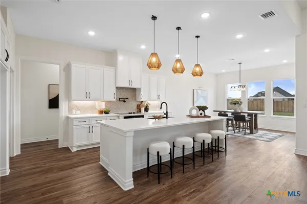 a kitchen with a dining table chairs sink and white cabinets