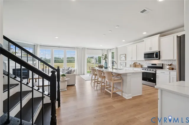 a kitchen with stainless steel appliances granite countertop a refrigerator sink and white cabinets