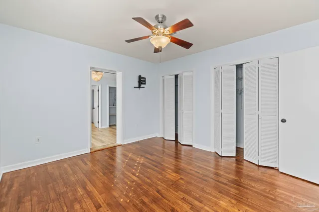 an empty room with wooden floor and ceiling fan