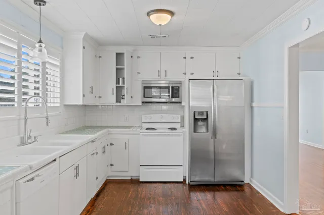 a kitchen with stainless steel appliances white cabinets and wooden floors