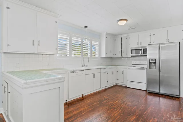 a kitchen with white cabinets white stainless steel appliances and sink