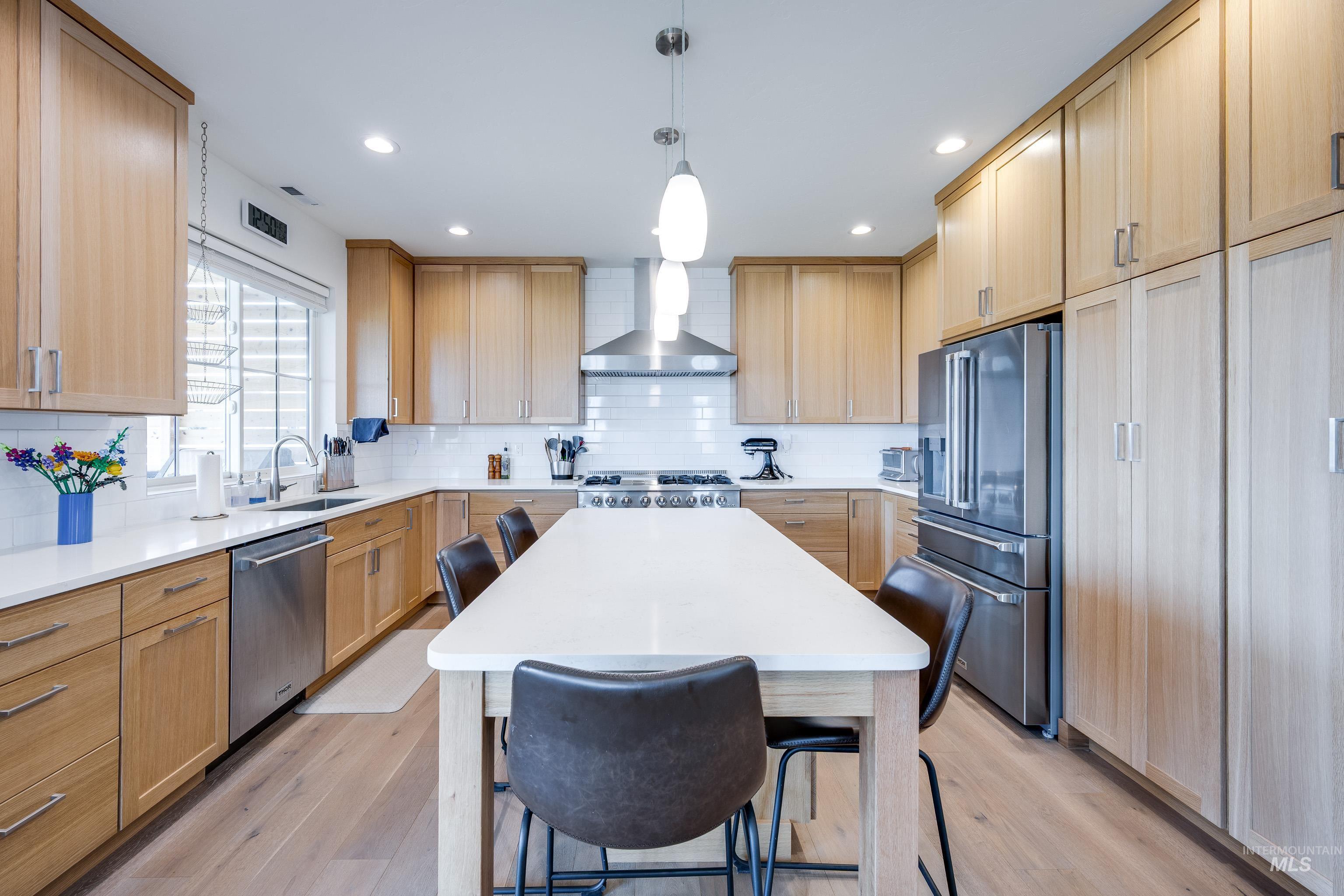 1325 Southwest Panorama Drive Pullman, WA 99163 - Photo 13 of 48 Kitchen with a breakfast bar area, stainless steel appliances, decorative backsplash, light wood-type flooring, and hanging light fixtures