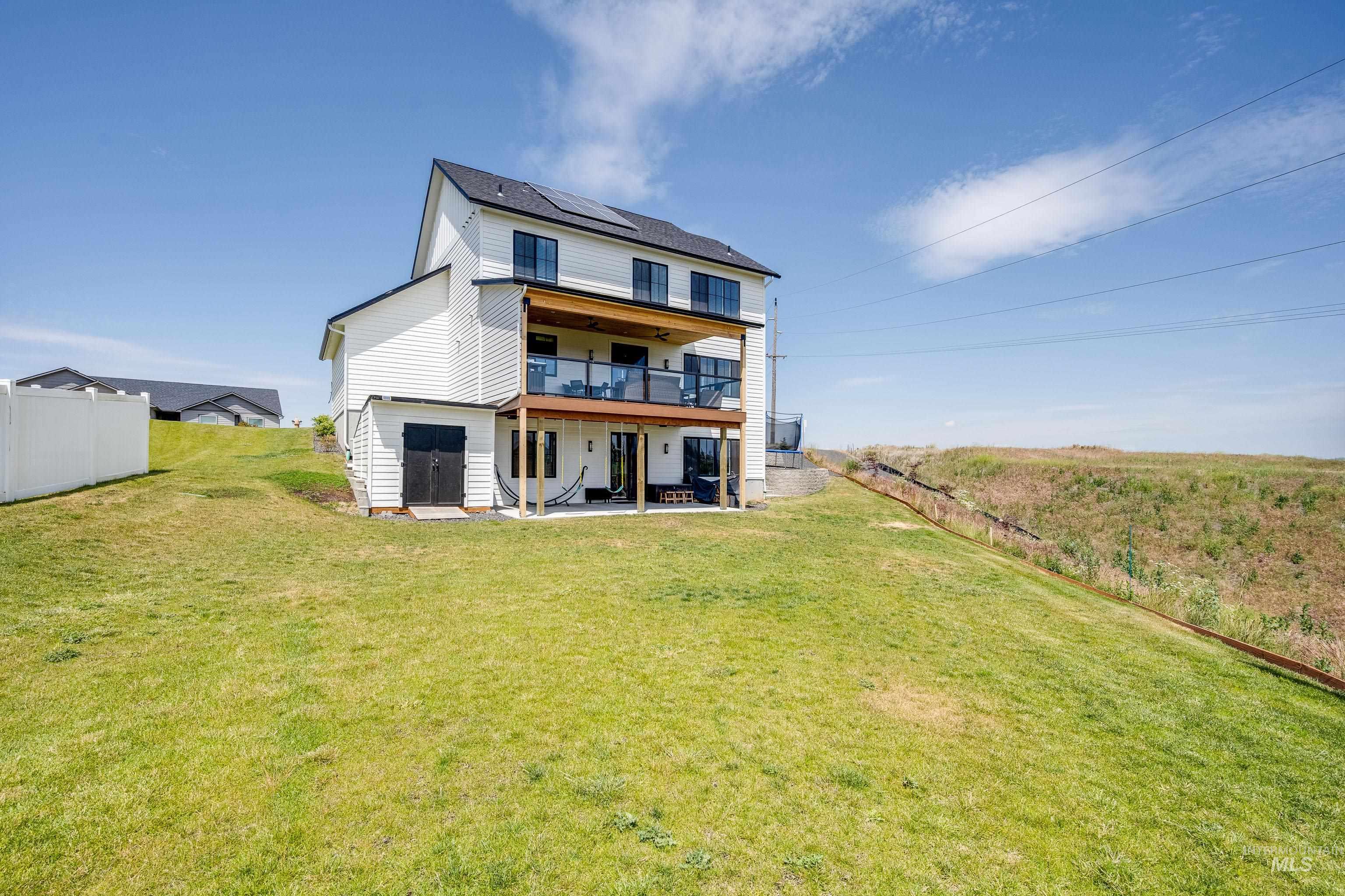 1325 Southwest Panorama Drive Pullman, WA 99163 - Photo 34 of 48 Back of property featuring a patio, a fenced backyard, and roof mounted solar panels