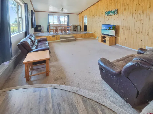 a living room with couches and kitchen view with wooden floor