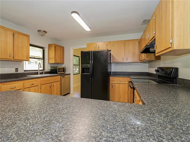 a kitchen with stainless steel appliances granite countertop a refrigerator a stove and a sink