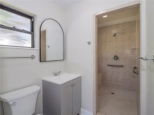 a bathroom with a shower sink vanity mirror and toilet