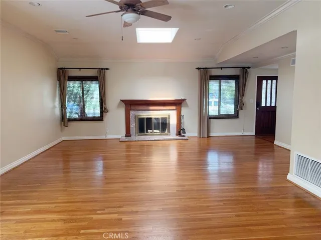 an empty room with wooden floor fireplace and windows