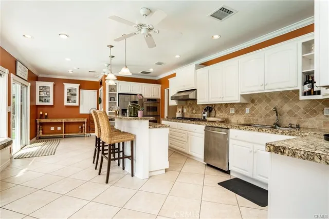 a kitchen with stainless steel appliances kitchen island granite countertop a table chairs sink and cabinets