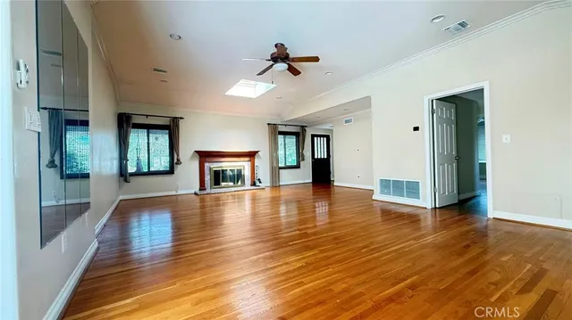 a view of a livingroom with wooden floor and a kitchen