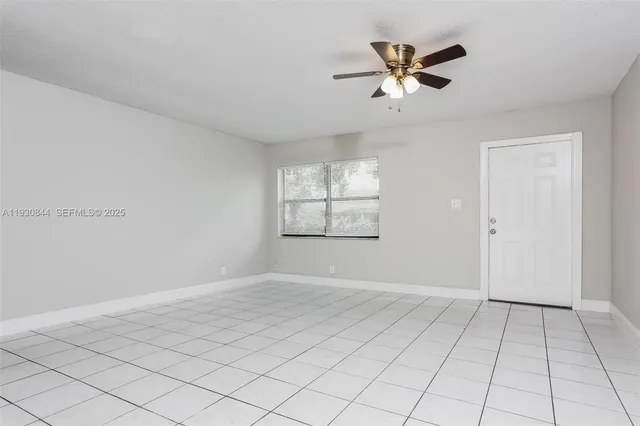 an empty room with windows and ceiling fan