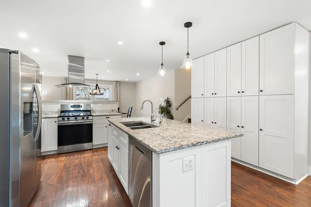 a kitchen with a center island white cabinets and stainless steel appliances