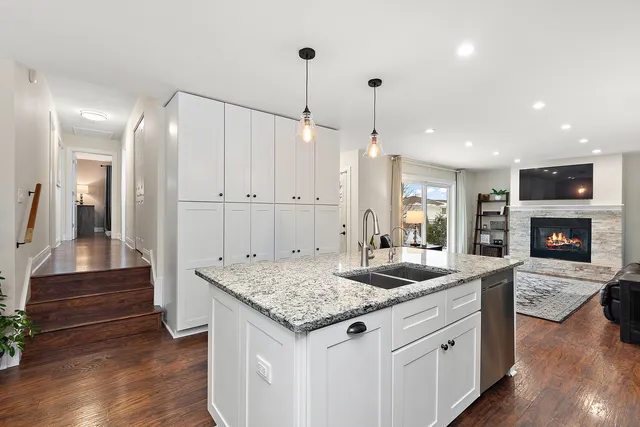 a kitchen with granite countertop kitchen island a sink appliances and a wooden floor