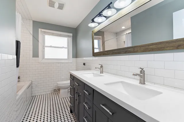 a bathroom with a sink a toilet a mirror and shower