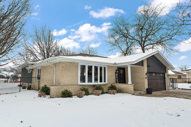 a front view of a house with a yard covered in snow