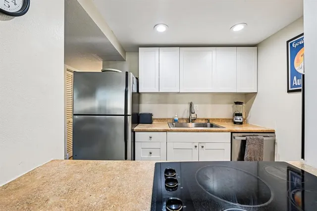 a kitchen with kitchen island a stove a refrigerator and a sink with wooden floor