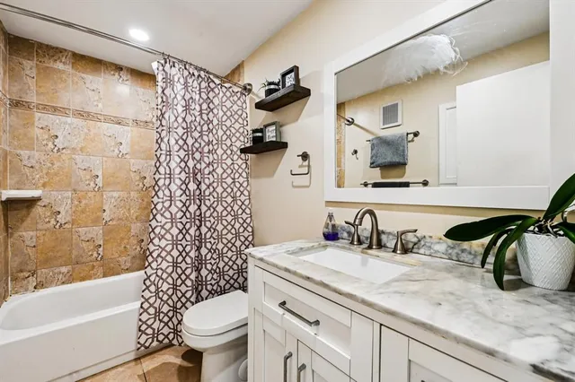a bathroom with a granite countertop sink a toilet and a bathtub