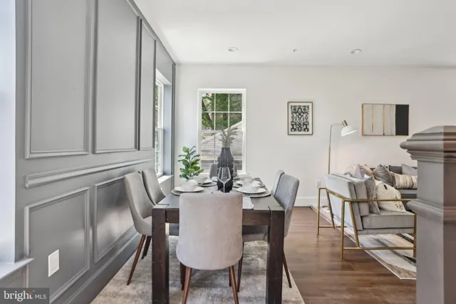 a kitchen with kitchen island granite countertop a dining table chairs and white cabinets with wooden floor