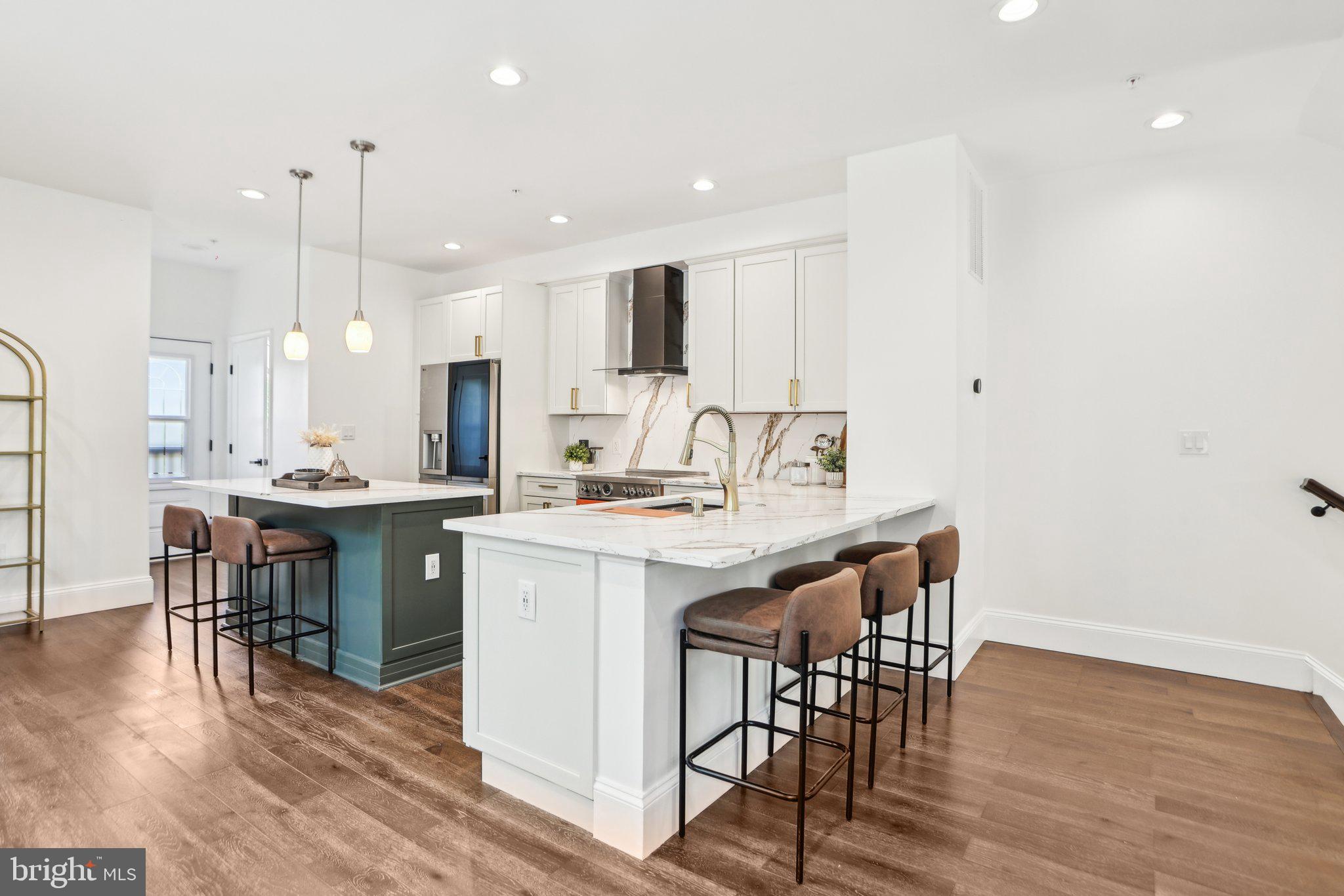 322 56th Street Northeast Washington, DC 20019 - Photo 18 of 57 a kitchen with kitchen island granite countertop a dining table chairs and white cabinets with wooden floor