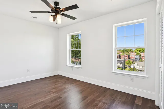 an empty room with wooden floor fan and windows