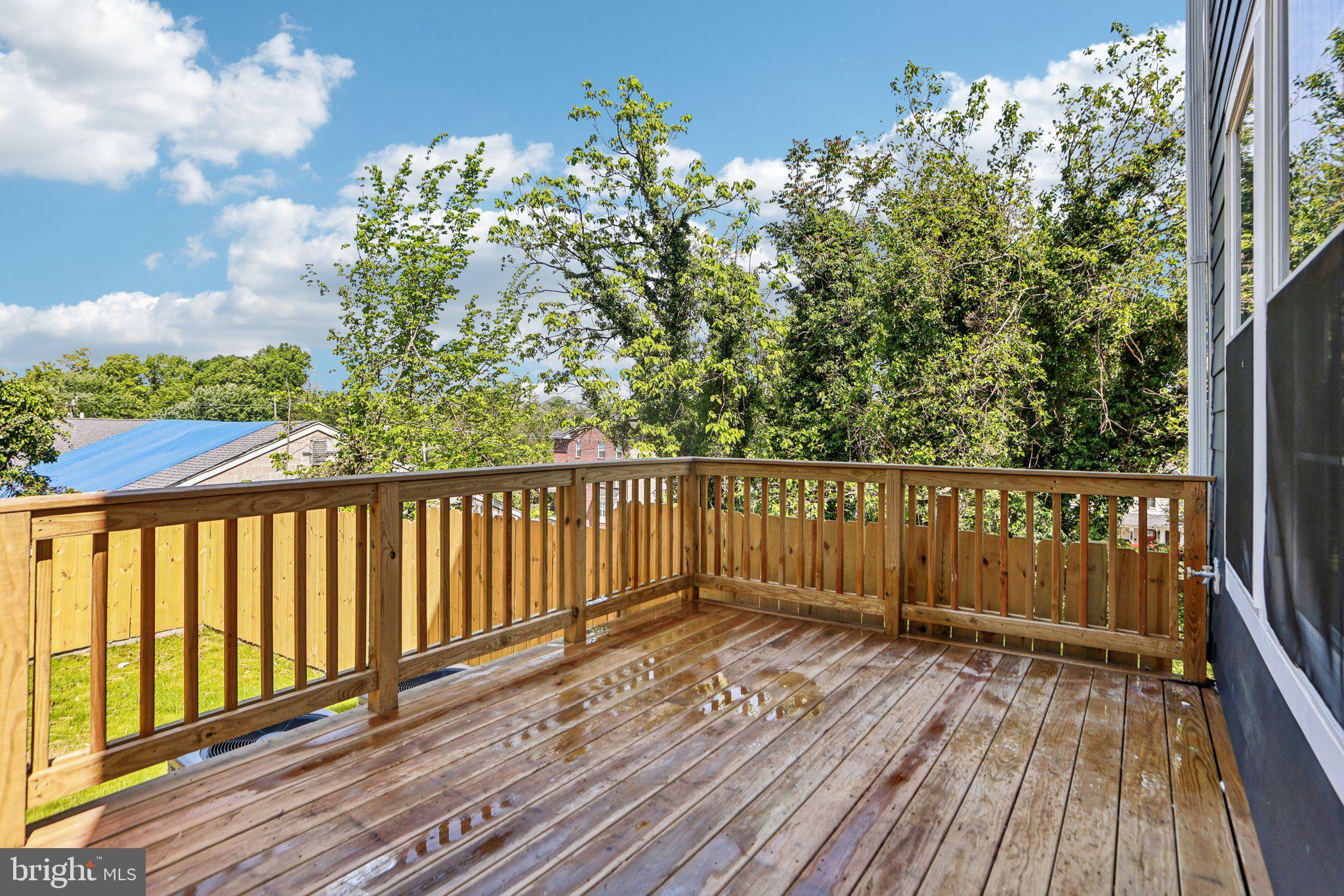 322 56th Street Northeast Washington, DC 20019 - Photo 48 of 57 a balcony with wooden floor and trees in the back
