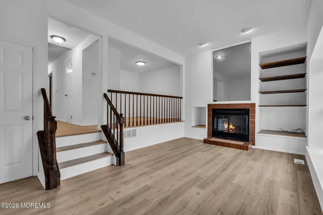 a view of empty room with wooden floor and fireplace