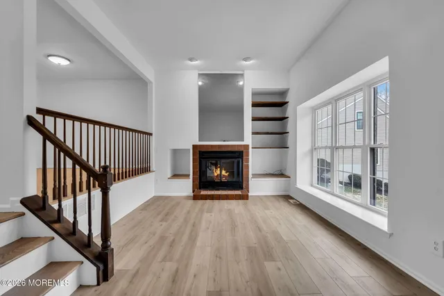a view of an empty room with wooden floor fireplace and a window