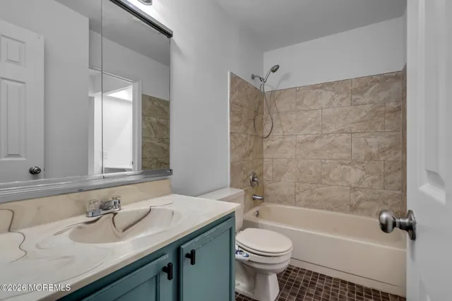 a bathroom with a granite countertop sink a toilet a mirror a bathtub and shower